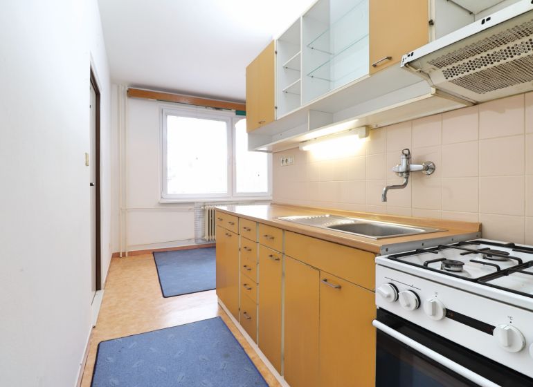 Küche in einer 2-Zimmer-Wohnung mit Küchenzeile, Herd und großem Fenster.