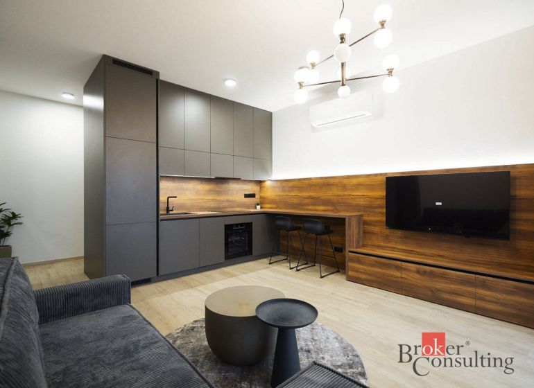 Küche in einer 2-Zimmer-Wohnung mit Holzboden und Wandfernseher.
