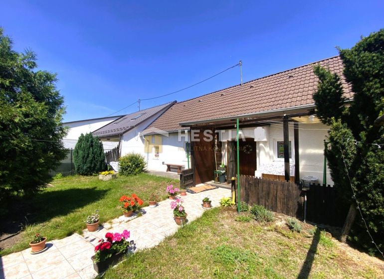 Ein Einfamilienhaus in Borský Mikuláš mit Garten, Blumen und Rasen im sonnigen Hof.