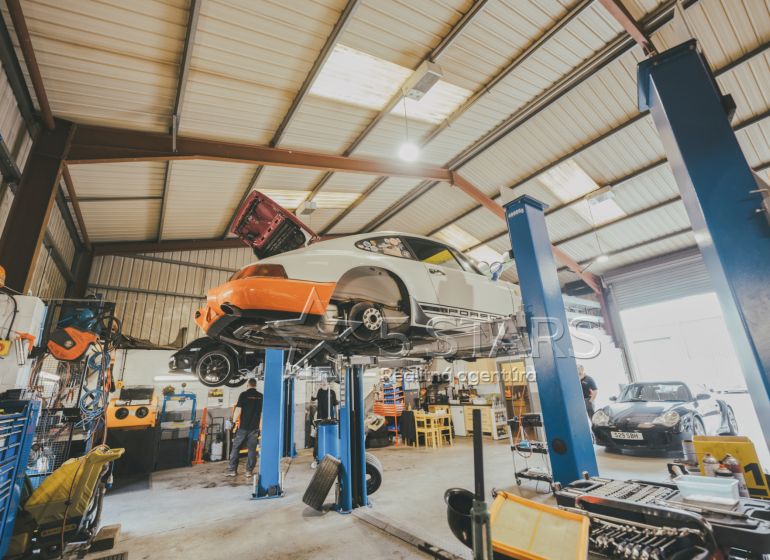 Auto-Service mit zwei Hebebühnen, Fahrzeugen und Werkzeugen in einem speziellen Immobilienbereich.