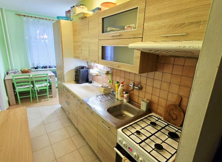 Küche in einer 4-Zimmer-Wohnung mit Holzelementen und Essecke.