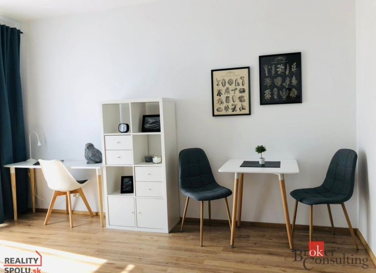 Innenraum einer Einzimmerwohnung mit Holzboden und stilvollen Stühlen.