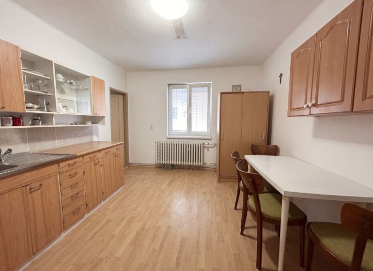 Eine Küche in einem Einfamilienhaus mit einem Boden in Holzoptik, Holzschränken und einem Esstisch.