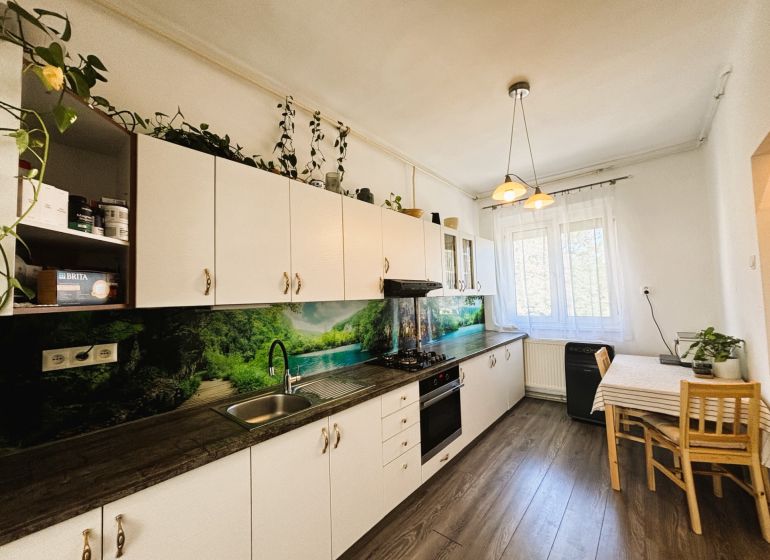 Küche mit Küchenzeile, Tisch und Boden mit Holzdekor in einer 2-Zimmer-Wohnung.