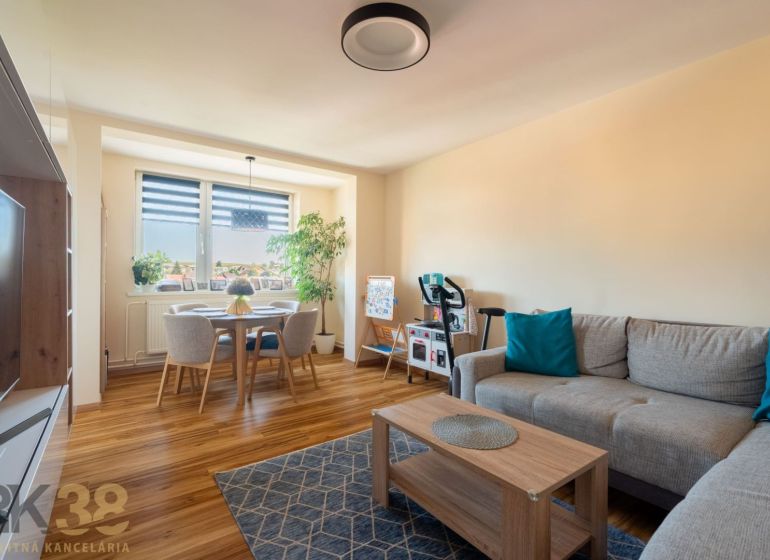 Wohnzimmer mit Sofa und Esstisch, Boden mit Holzdekor.
