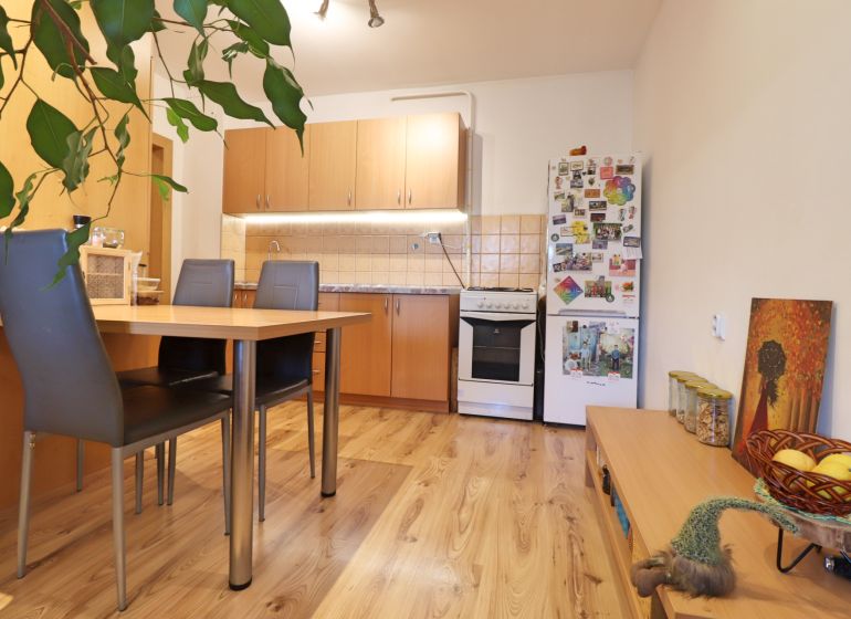 Küche in einer 2-Zimmer-Wohnung mit Holzboden, Esstisch und Kühlschrank.