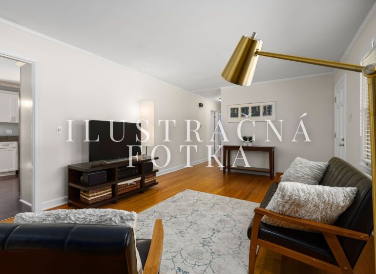 Wohnzimmer in einer 3-Zimmer-Wohnung, mit Sofa und Fernseher, Boden mit Holzdekor.