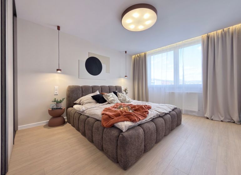 Helles Schlafzimmer mit großem Bett und Holzboden in einer 3-Zimmer-Wohnung.