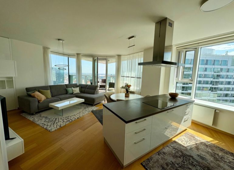 Helles Wohnzimmer mit Holzboden in einer 3-Zimmer-Wohnung, mit Blick aus großen Fenstern.