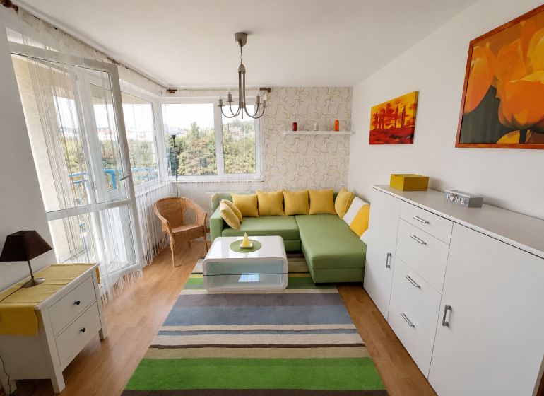 Wohnzimmer mit Ecksofa, Holzboden und buntem Teppich.