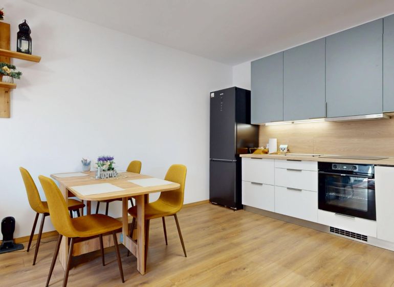Küche in einer 2-Zimmer-Wohnung mit Holzboden, Esstisch und Geräten.