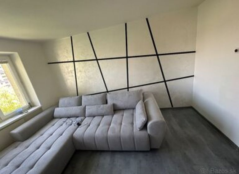 Innenraum einer 2-Zimmer-Wohnung mit einem bequemen Sofa und einem Boden in Holzoptik.