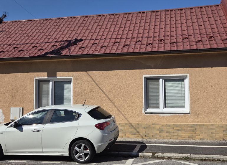 Ein Einfamilienhaus in Trnava mit einem roten Dach und einem weißen Auto, das vor dem Haus geparkt ist.