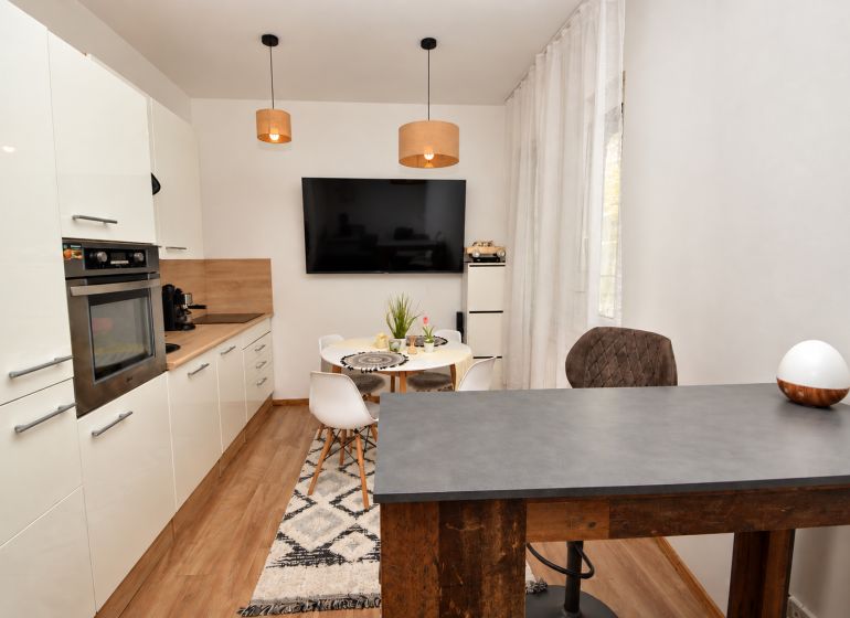 Küche in einer Einzimmerwohnung mit Holzboden und Esstisch.