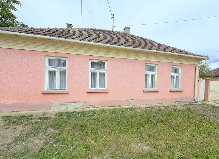 Ein Einfamilienhaus in Dunakiliti mit rosa Fassade und vier Fenstern im Erdgeschoss.