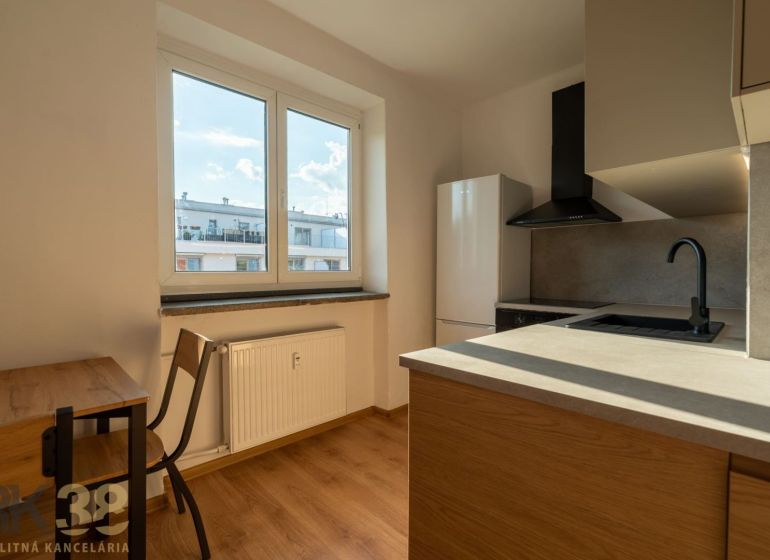 Küche in einer Einzimmerwohnung mit Holzboden und Blick aus dem Fenster.