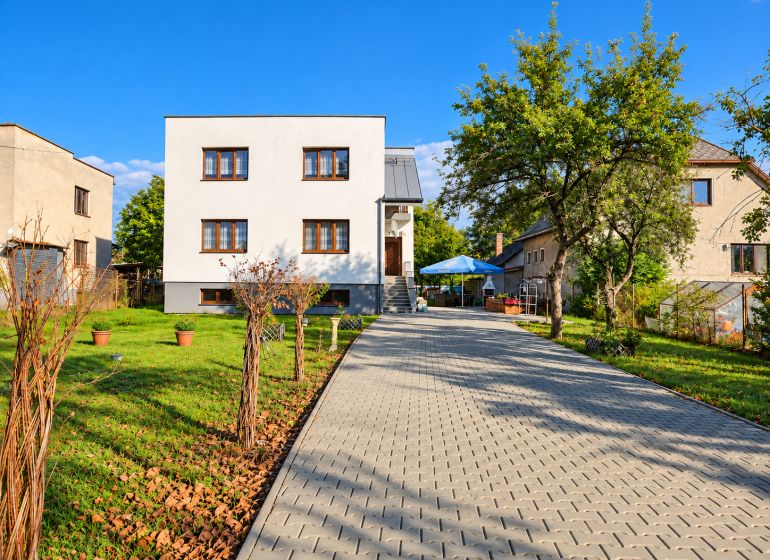 Ein Einfamilienhaus in Martin mit Zufahrtsstraße und Garten, umgeben von Grünflächen und Bäumen.