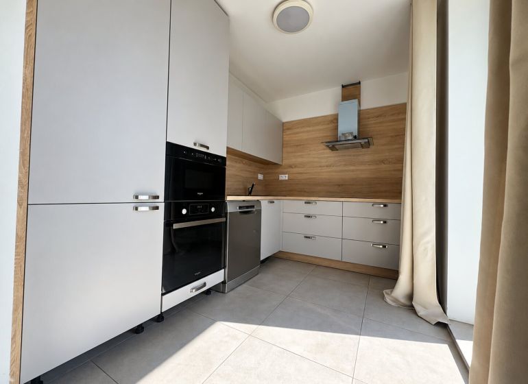 Küchenzeile in einer 2-Zimmer-Wohnung, helle Elemente, Boden mit Holzdekor, eingebaute Geräte.