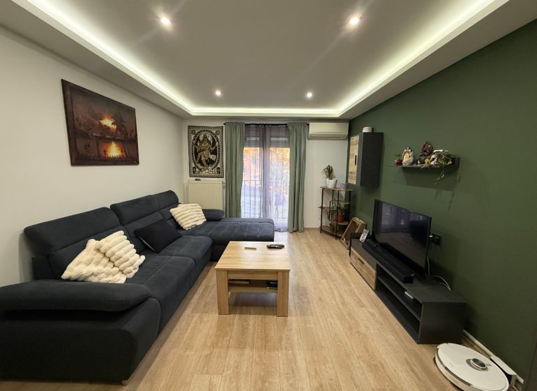 Wohnzimmer in einer Zweizimmerwohnung mit Holzboden und Sofa.