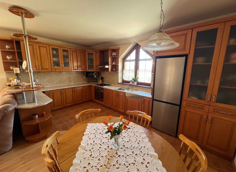 Die Küche eines Einfamilienhauses mit Holzmöbeln, einem Boden mit Holzdekor und einem Esstisch.