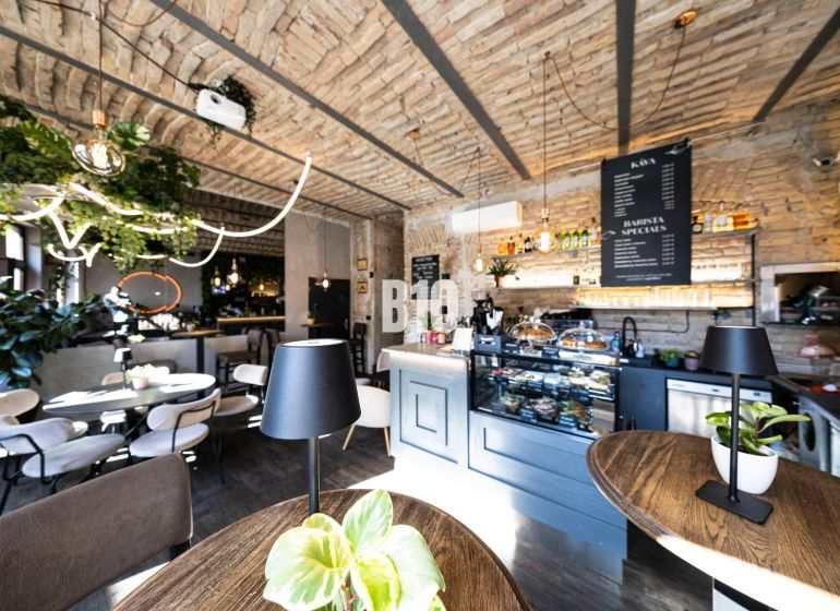 Stilvolle Gastronomiebereiche mit Backsteingewölben, Grünpflanzen und einem Boden in Holzoptik.