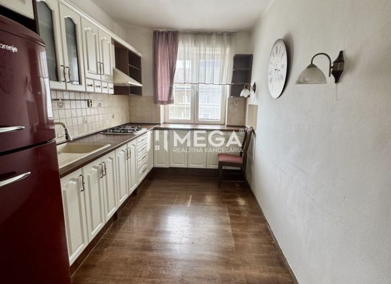 Küche in einer 3-Zimmer-Wohnung mit Holzboden, weißen Möbeln, rotem Kühlschrank.