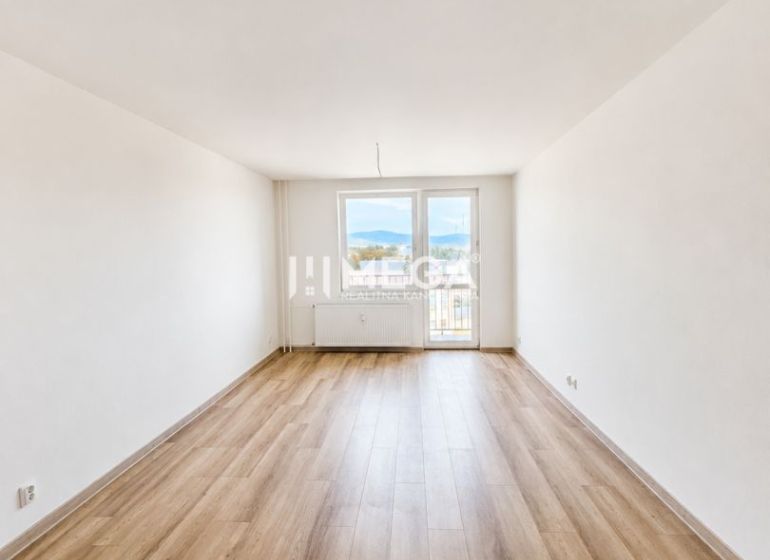Geräumiges Wohnzimmer mit Zugang zum Balkon und Holzboden in einer 2-Zimmer-Wohnung.