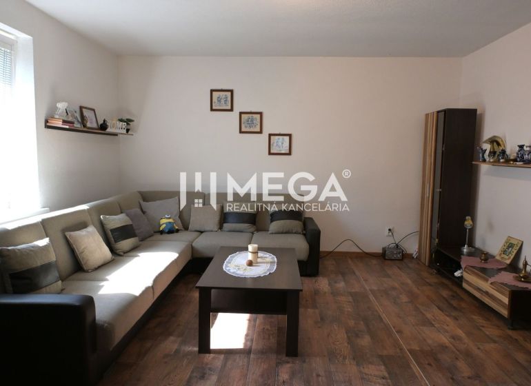Wohnzimmer mit Sofa, Tisch und Holzboden in einem Einfamilienhaus.