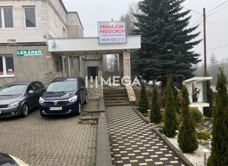 Gebäude in der SNP-Straße in Snina mit Parkplatz und Werbung für die Vermietung von Räumlichkeiten.