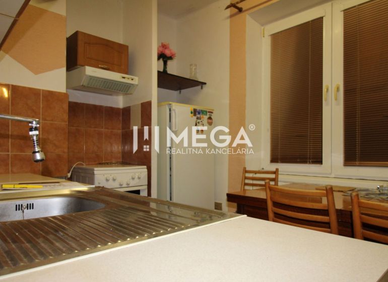 Küche in einer 3-Zimmer-Wohnung mit Spüle, Kühlschrank, Herd und Holzstühlen.