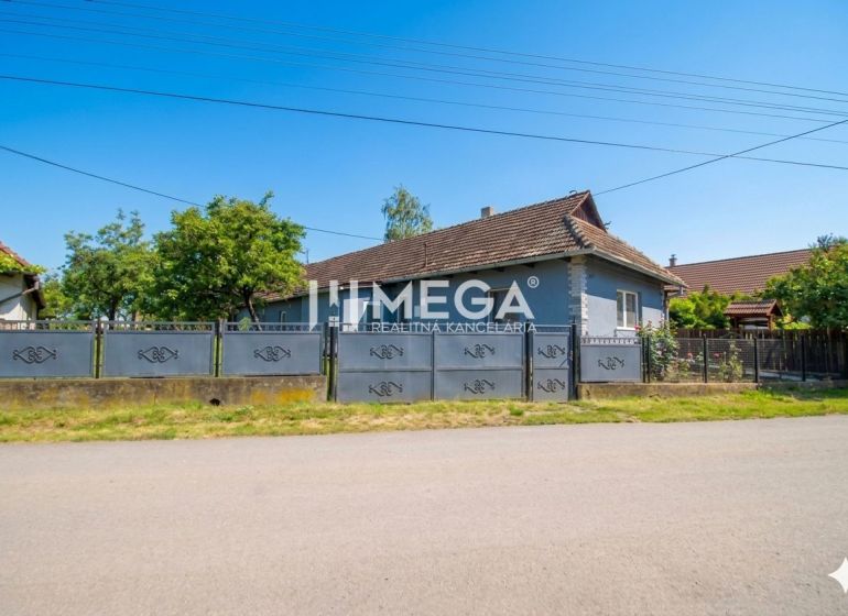Ein Einfamilienhaus in Veľká Ida mit einem großen Tor und Garten in einer ruhigen Straße.