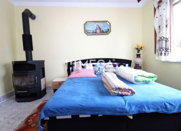 Interieur eines Einfamilienhauses mit Bett, Kachelofen und bunten Accessoires.
