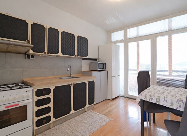 Küche in einer 3-Zimmer-Wohnung mit Holzboden und Essecke.