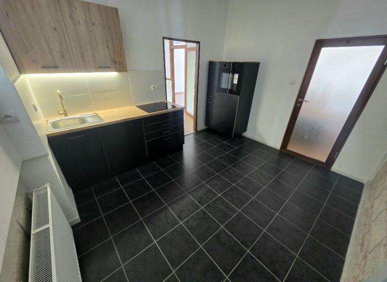 Küche in einer 2-Zimmer-Wohnung mit schwarzen Schränken und strukturiertem Boden.