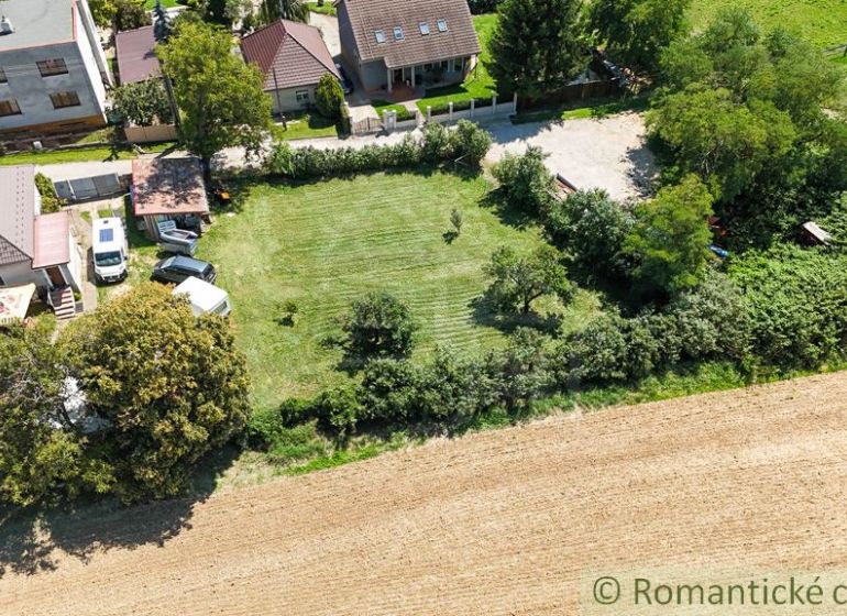 Häuser mit Gärten in Pastuchov, umgeben von Feldern und Grünflächen.