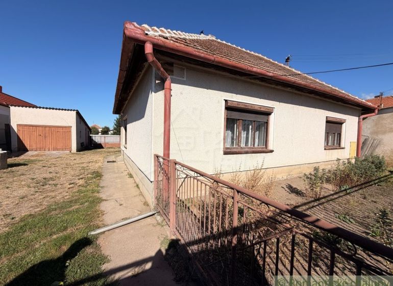 Ein Einfamilienhaus in Hurbanovo mit einem großen eingezäunten Garten, einer angrenzenden Garage und einem Rasenstück.