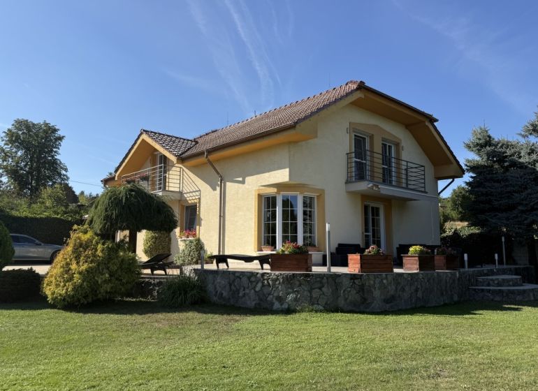 Ein Einfamilienhaus in Zlaté Moravce, umgeben von Grün, mit einer Steinterrasse und einem Balkon.