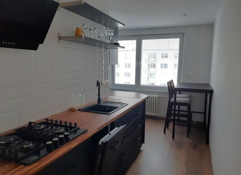 Küche in einer 2-Zimmer-Wohnung mit Holzboden und Bartisch.