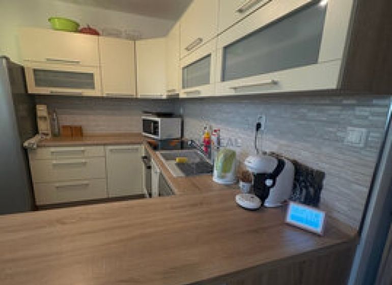 Küche in einer 2-Zimmer-Wohnung mit Holzboden und hellen Möbeln.