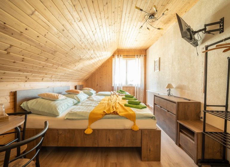 Ein Zimmer mit Holzverkleidung, einem Doppelbett, einem Fernseher und einem Boden mit Holzdekor. Hotels und Pensionen.