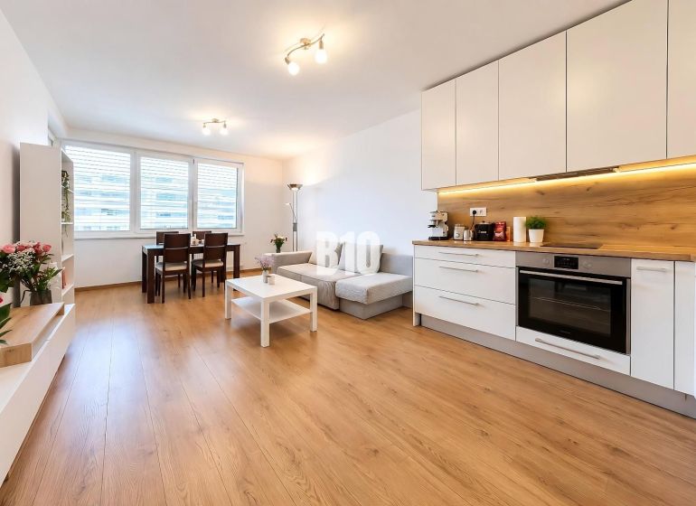 Wohnbereich mit Küche und Holzboden in einer Zweizimmerwohnung.