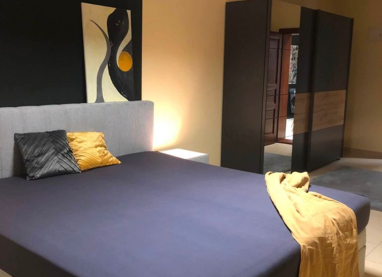 Schlafzimmer mit Doppelbett, Kleiderschrank und abstrakter Kunst in einer 2-Zimmer-Wohnung.