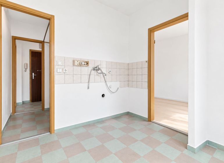 Geräumige Küche in einer 2-Zimmer-Wohnung mit Fliesen an den Wänden.