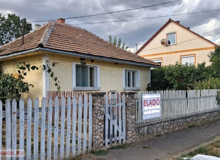Ein Einfamilienhaus in Tornyosnémeti mit einem Ziegeldach und einem bunten Zaun.