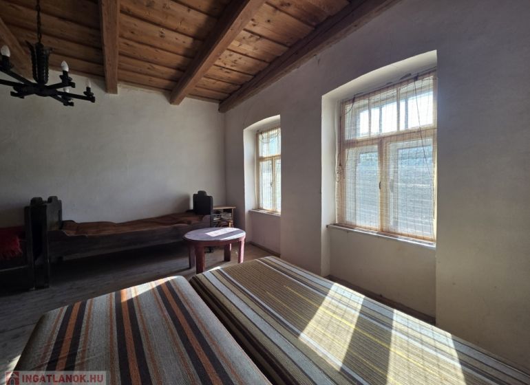 Ein Zimmer in einem Einfamilienhaus mit Holzbalkendecken und natürlichem Licht.