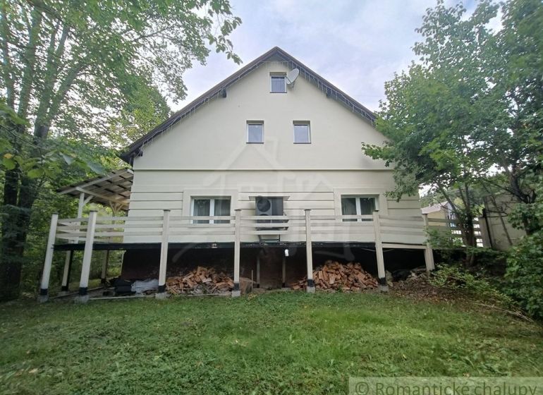 Ein Einfamilienhaus in Staškov, umgeben von Grün, mit Holz unter der Terrasse gelagert.