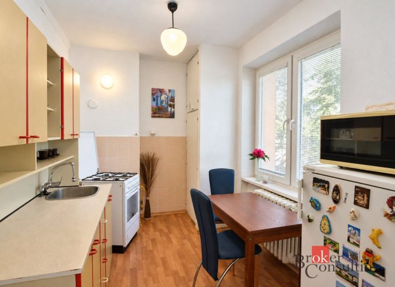 Küche in einer 2-Zimmer-Wohnung mit Holzboden, Esstisch und moderner Ausstattung.