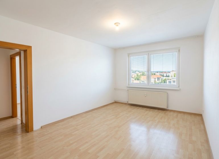 Ein Zimmer in einer 3-Zimmer-Wohnung mit einem großen Fenster und einem Boden in Holzoptik.