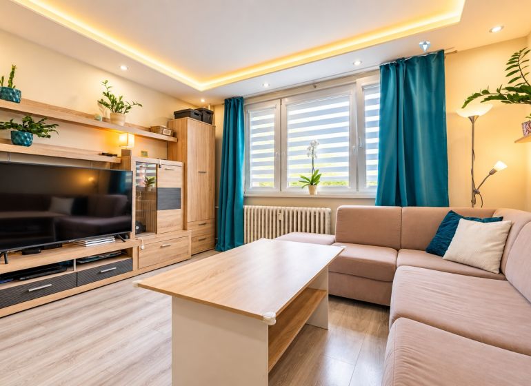 Wohnzimmer mit Sofa, Fernseher und Holzboden in einer 3-Zimmer-Wohnung.