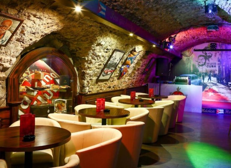 Eine Bar in historischen Gastronomieräumen mit Steinwänden und einem Boden in Holzoptik.